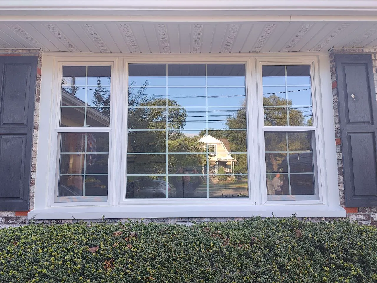 Triple window unit — a picture window flanked by gridded double-hungs — on a brick facade